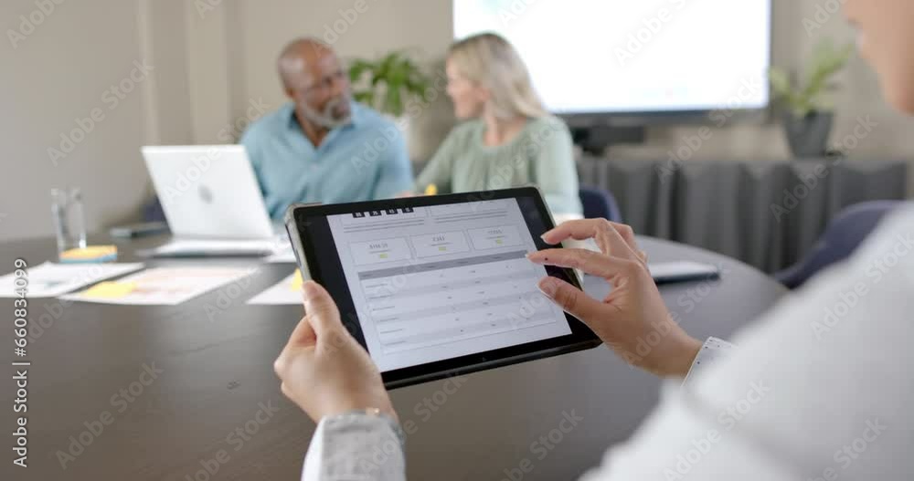 Diverse business people using laptop and tablet at conference table with copy space Diverse business people using laptop and tablet at conference table with copy space