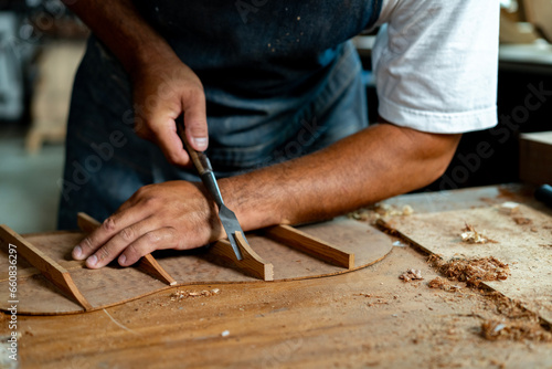 Obraz na plátně Close-up of guitar luthier using chisel to shave bracing of acoustic guitar