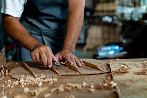 Guitar luthier using small planer to fine-tune bracing of acoustic guitar.