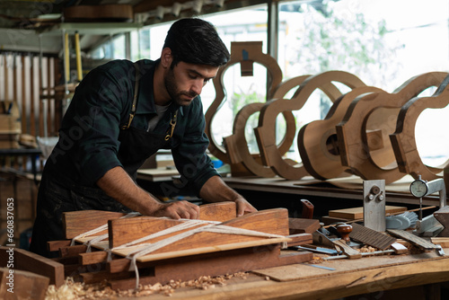Fotografie Guitar luthier ties rope, drives wedge to join spruce wood boards