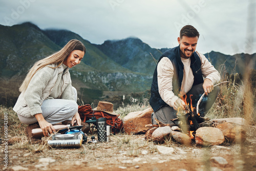 Couple, camping and fire in nature, mountains and outdoor for sustainable heating, vacation and prepare kettle. Happy man and woman in field with water, campfire or flames for cooking on holiday photo
