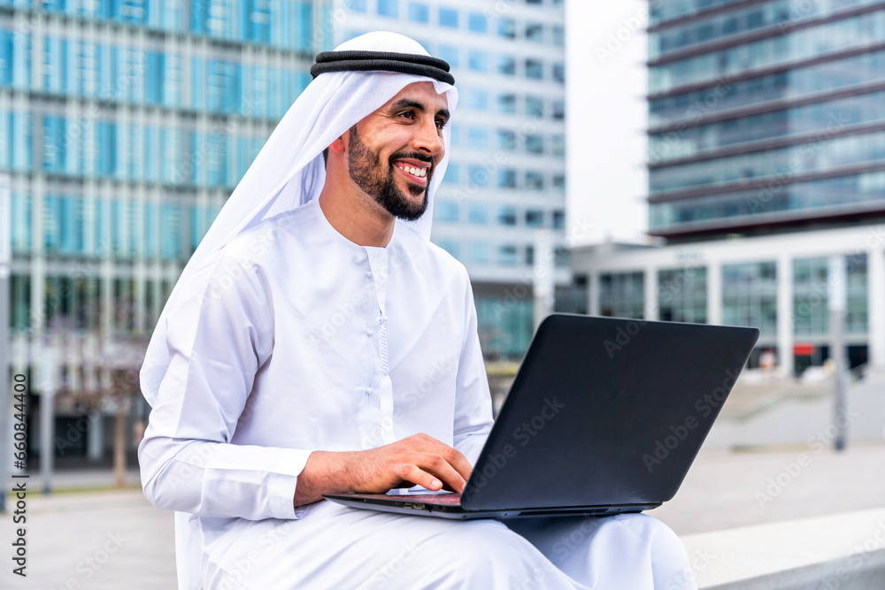 Arab middle-eastern man wearing emirati kandora traditional clothing in the city - Arabian muslim businessman strolling in urban business centre. Arab middle-eastern man wearing emirati kandora traditional clothing in the city - Arabian muslim businessman strolling in urban business centre.