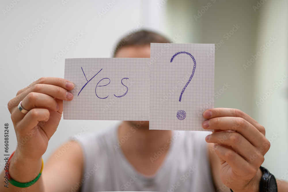Młody mężczyzna trzyma kartkę z napisem "tak?" - obrazy, fototapety, plakaty 