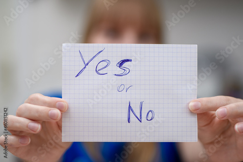 Kobieta trzyma kartki z pytaniem tak czy nie
