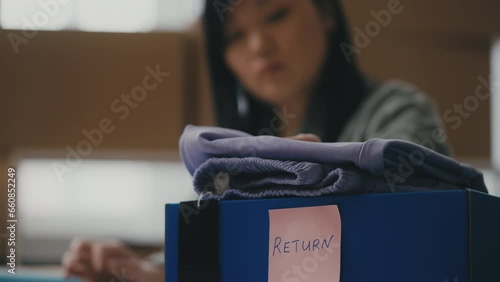 Asian woman clothing store owner processes returned orders, checks the items