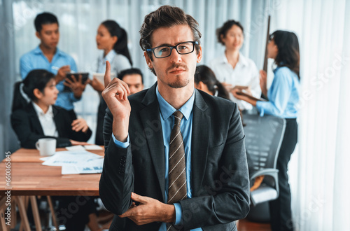 Portrait of happy businessman looking at camera  making finger pointing gesture for advertising product with motion blur background of business people movement in dynamic business meeting. Habiliment