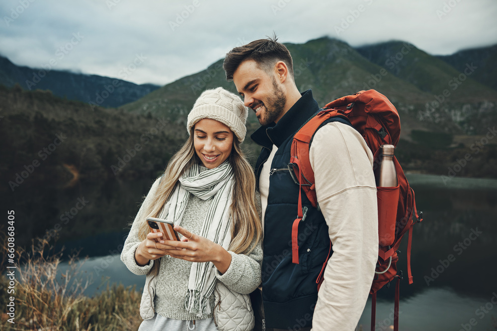 Couple, phone and hiking in nature, mountains or lake with social media, travel contact and internet connection. Happy people in backpack and mobile, chat or search for outdoor location or direction