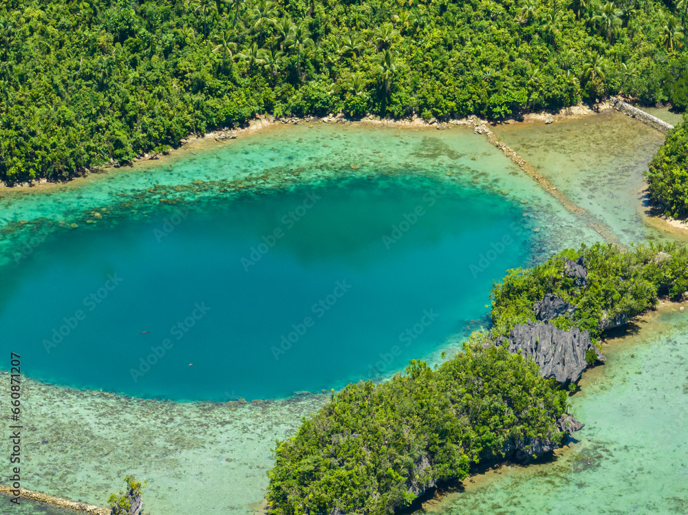 Birds eye view of turquoise water in lagoons of Tropical Island. Coral reefs under blue sky and clouds. Mindanao, Philippines.