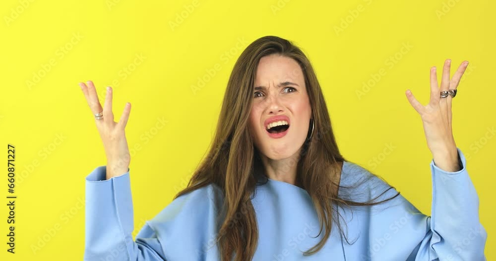 Close up of annoyed irritated young woman with an angry face looking furious, mad and feeling frustrated isolated on yellow background. Brunette girl expressions and emotions. Close up of annoyed irritated young woman with an angry face looking furious, mad and feeling frustrated isolated on yellow background. Brunette girl expressions and emotions.