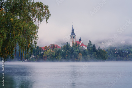 Famous alpine Bled lake (Blejsko jezero) in dense fog, amazing misty landscap...