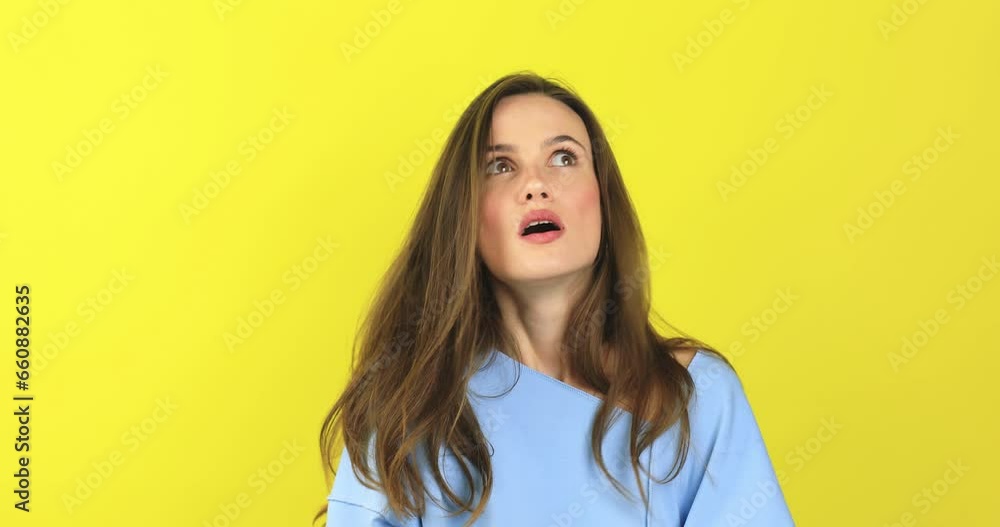 Close up of annoyed irritated young woman with an angry face looking furious, mad and feeling frustrated isolated on yellow background. Brunette girl expressions and emotions, wear blue sweater. Close up of annoyed irritated young woman with an angry face looking furious, mad and feeling frustrated isolated on yellow background. Brunette girl expressions and emotions, wear blue sweater.