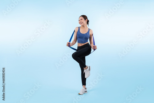 Fototapeta Naklejka Na Ścianę i Meble -  Vigorous energetic woman in sportswear portrait stretching resistance sport band. Young athletic asian woman strength and endurance training session workout routine concept on isolated background.