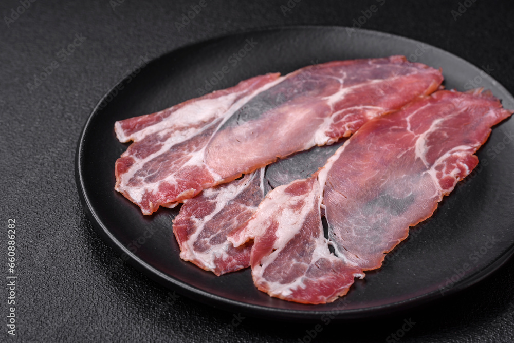 Slices of delicious smoked jamon or prosciutto with salt, spices and herbs