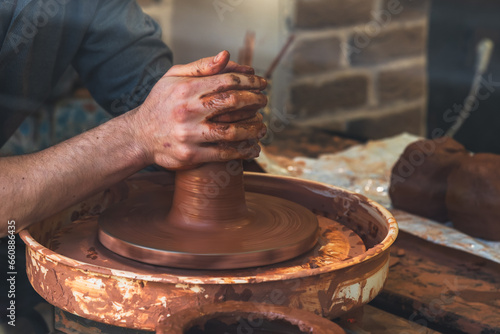 The skillful hands of a potter form a product on a potter's wheel. Traditional crafts. DIY ceramics.