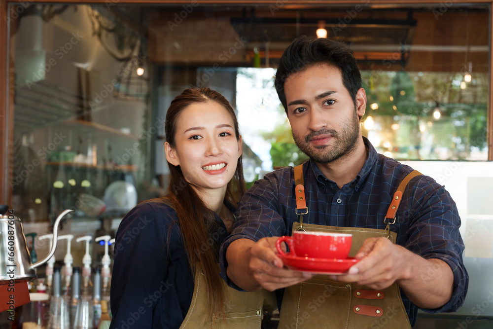 Asian man and woman couple owning a bakery together Holding a red coffee cup outstretched in front of you to deliver to customers who come to use the service in the cafe