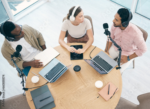Laptop, podcast or broadcast with a content creator team in their office from above for streaming or recording. Radio, microphone and influencer friends in the studio together on a creative platform