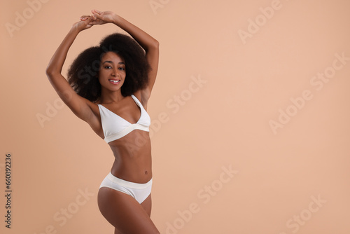 Beautiful woman in stylish bikini on beige background, space for text