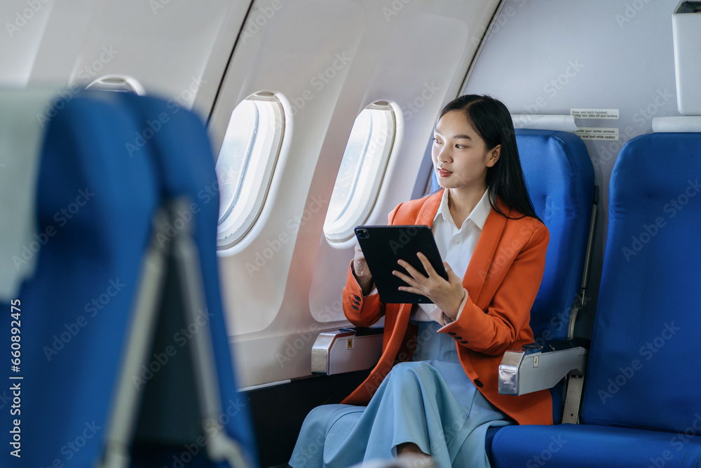 Traveling and technology. young business woman working on Tablet while sitting in airplane. - obrazy, fototapety, plakaty 
