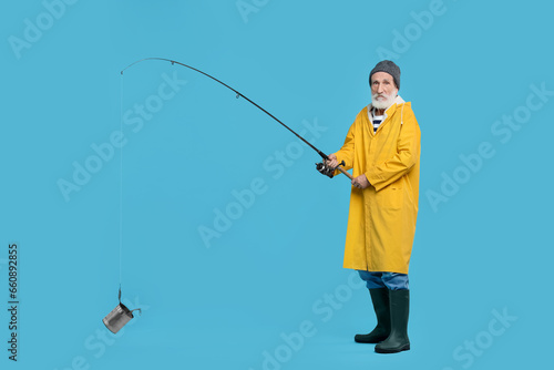 Fisherman with fishing rod and tin can on light blue background, space for text