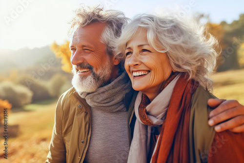 Older couple hugging smiling outdoors.