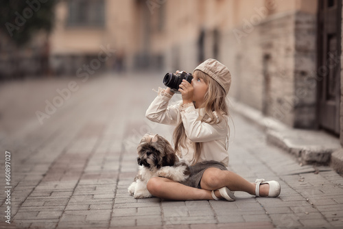 Little girl with camera and puppy taking photos on the streets of the city 