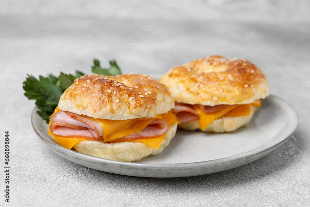 Delicious bagels with ham and cheese on light table, closeup
