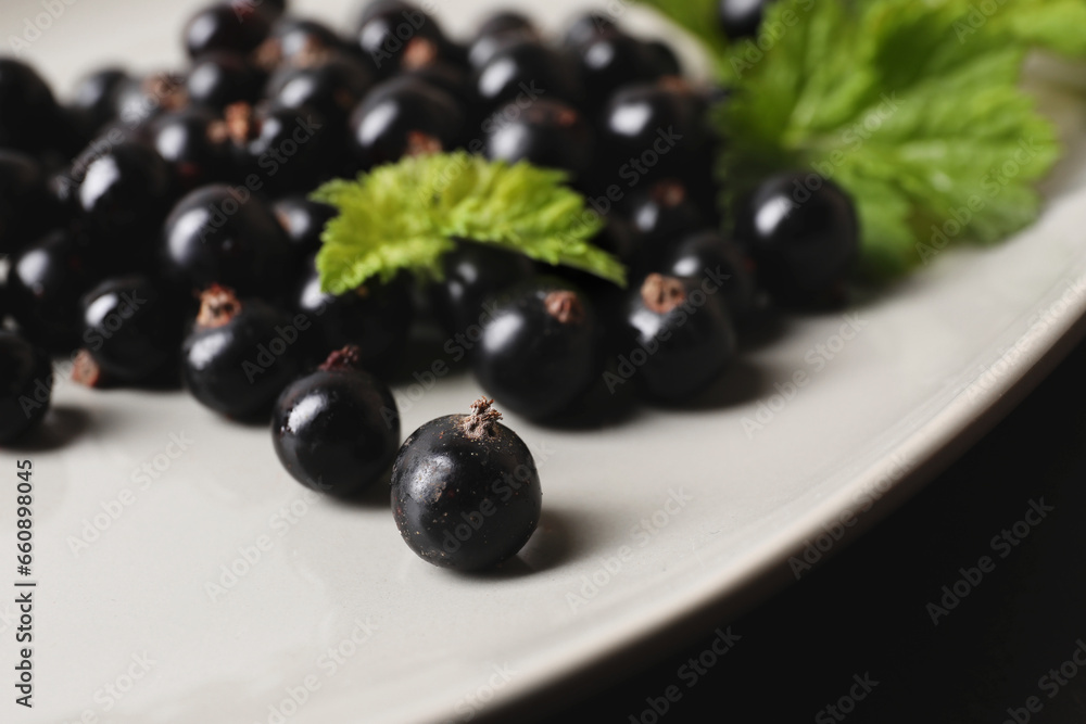 Ripe blackcurrants and leaves on plate, closeup Ripe blackcurrants and leaves on plate, closeup