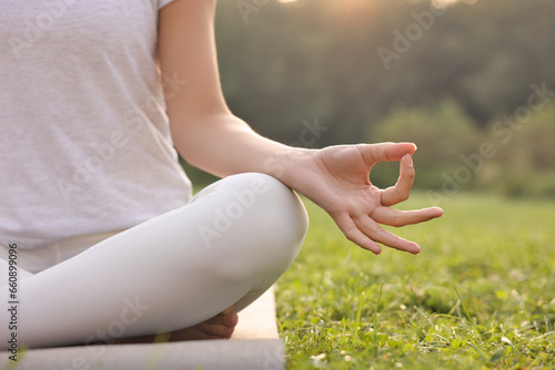 Woman practicing yoga on mat outdoors, closeup and space for text. Lotus pose
