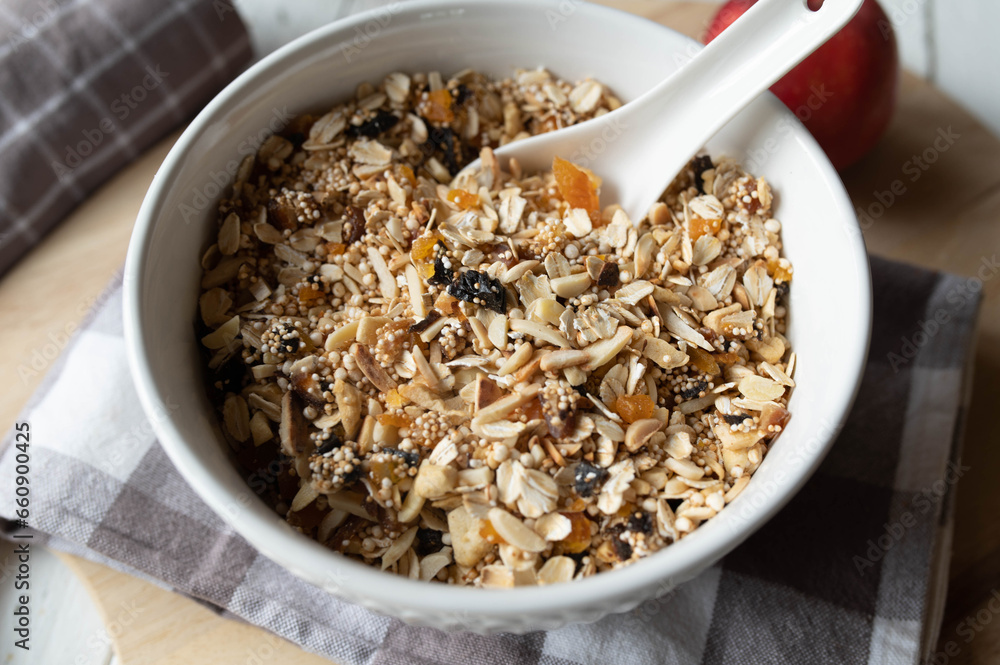 Homemade granola with oats, puffed amaranth, quinoa, almonds, dried fruits such as apricots, plums, apples, and dates in bowl with spoon Homemade granola with oats, puffed amaranth, quinoa, almonds, dried fruits such as apricots, plums, apples, and dates in bowl with spoon