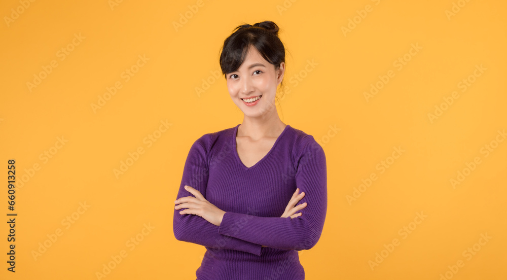 Obraz premium portrait cheerful young asian woman 30s wearing purple shirt happy smile crosses arm on chest isolated on yellow background.