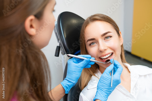 A female patient with an immaculate smile is receiving dental care from the dentist