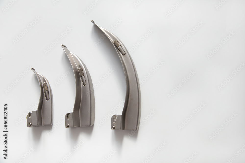 There are curved blades for a laryngoscope on a white table. Copy space. There are curved blades for a laryngoscope on a white table. Copy space.