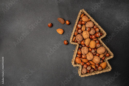 a set of nuts in a Christmas tree shaped basket on a dark background, banner, menu, recipe place for text, top view