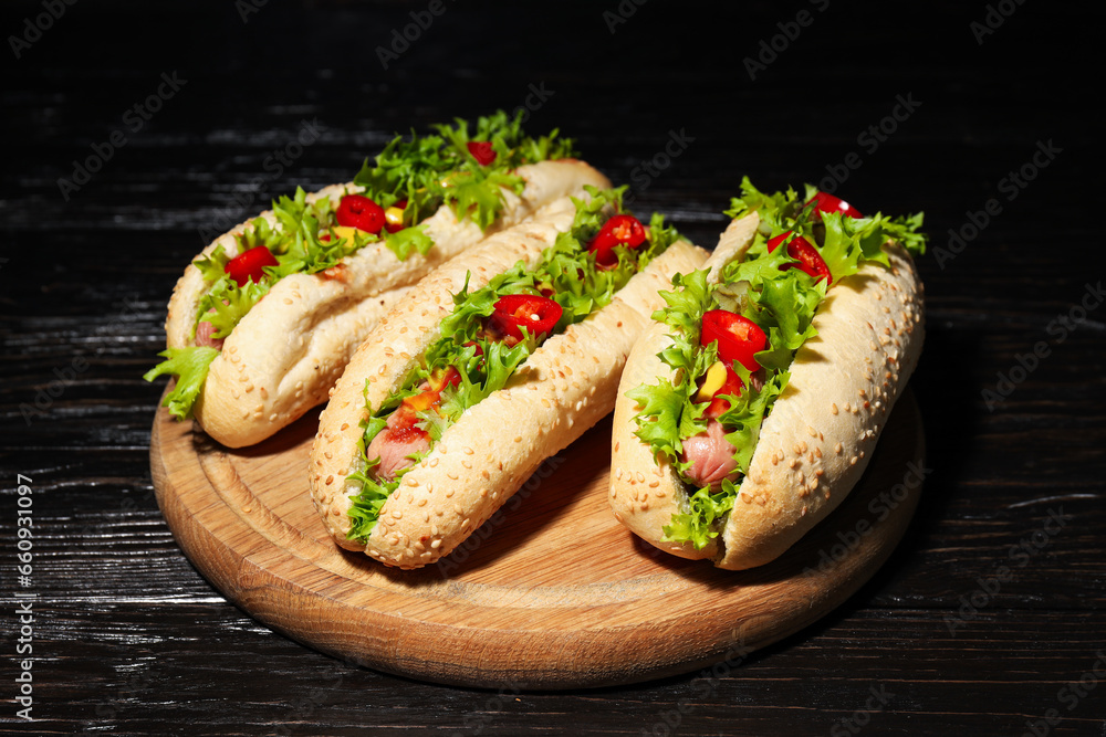 Hot dogs on board on wooden background, close up Hot dogs on board on wooden background, close up