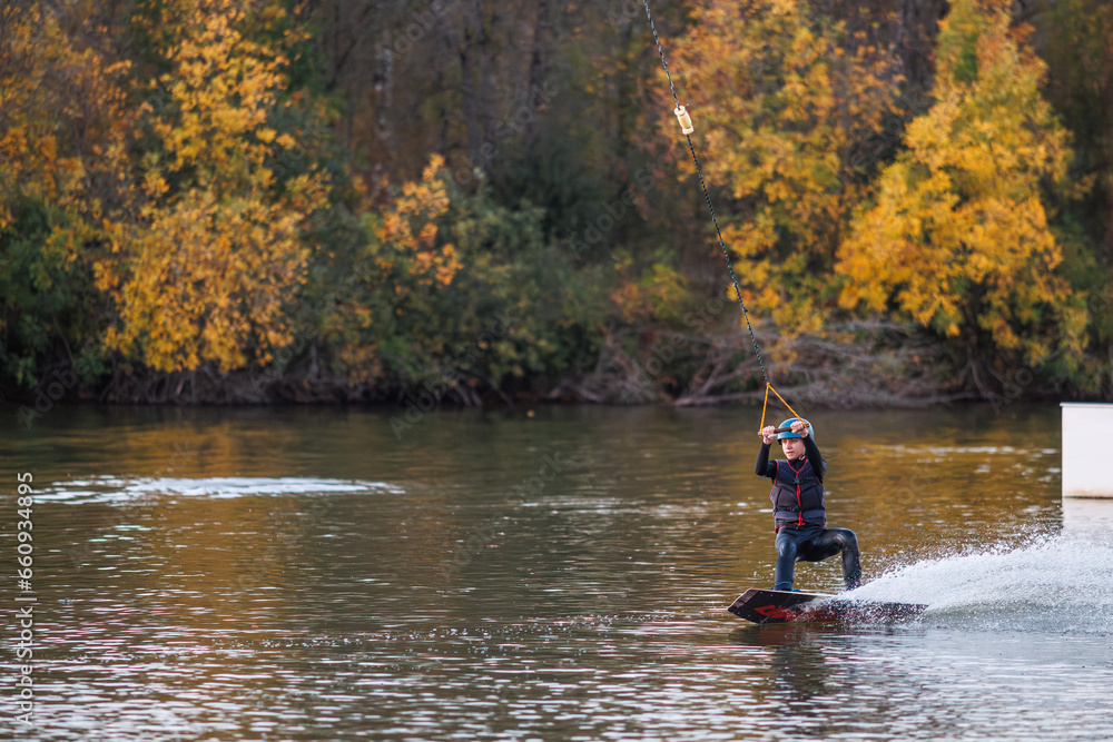 Girl on a wakeboard. An athlete performs a trick on the water. Autumn Park Girl on a wakeboard. An athlete performs a trick on the water. Autumn Park