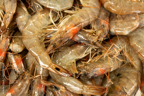 Unpeeled king prawns, popular seafood, on display at a market stall.