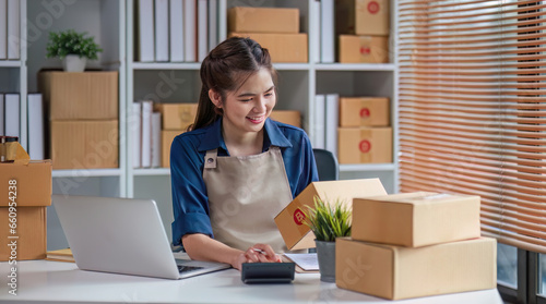 Portrait business Asian woman smile checking information on parcel shipping box before send to customer. Entrepreneur small business working at home. SME business online marketing.