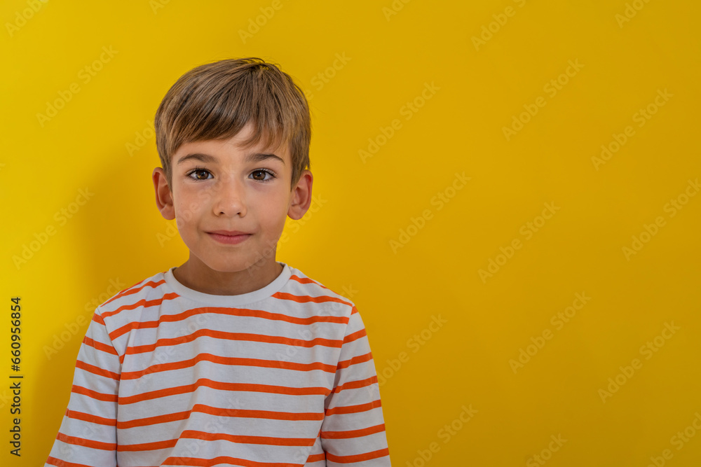 Portrait of happy joyful small caucasian boy in front of yellow background looking to the camera - Childhood growing up and concept - front view waist up copy space Portrait of happy joyful small caucasian boy in front of yellow background looking to the camera - Childhood growing up and concept - front view waist up copy space