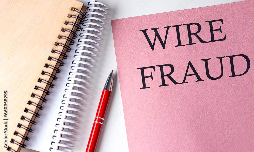 WIRE FRAUD word on the pink paper with office tools on white background WIRE FRAUD word on the pink paper with office tools on white background