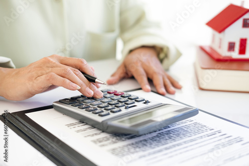 Hand of Business people calculating interest, taxes and profits to invest in real estate and home buying