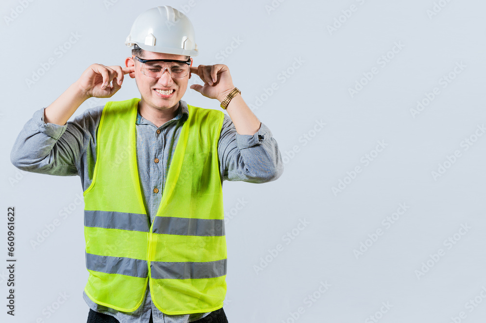 Young engineer covering ears isolated. Engineer man with ear pain. Concept of engineer covering his ears with pain expression