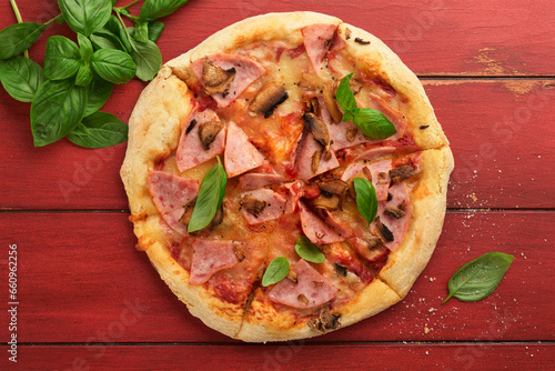 Pizza. Traditional Bacon pizza with ham, mushrooms, pickled cucumber and cheese and cooking ingredients tomatoes basil on wooden table backgrounds. Italian Traditional food. Top view. Mock up.