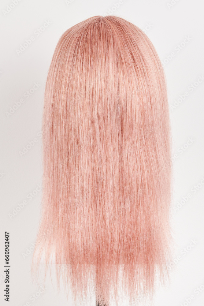 Natural looking pink blonde wig on white mannequin head. Long hair cut on the plastic wig holder isolated on white background Natural looking pink blonde wig on white mannequin head. Long hair cut on the plastic wig holder isolated on white background