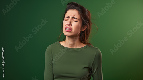 Depressed young woman crying on green background