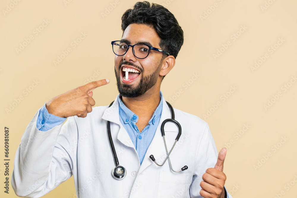 Smiling Indian Hindu doctor man puts of tablet pill white capsule into mouth, recommends drugs immunization cure treatment. Health care. Vitamins for joints, hair, skin, nails. Apothecary pharmacist Smiling Indian Hindu doctor man puts of tablet pill white capsule into mouth, recommends drugs immunization cure treatment. Health care. Vitamins for joints, hair, skin, nails. Apothecary pharmacist