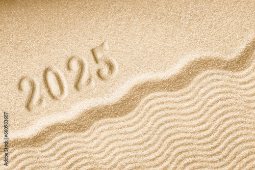 Imprints of numbers 2025 happy new year on a golden sand waves