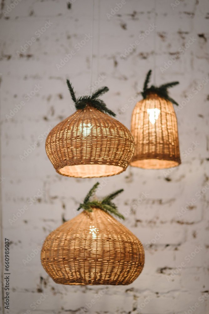 Obraz premium Pendant light with wicker lampshade, Christmas tree. Decorative ceiling shade lamp. Decorating hanging lantern lamps rattan in vine bamboo. Christmas decor interior at home. Concept of winter holiday.