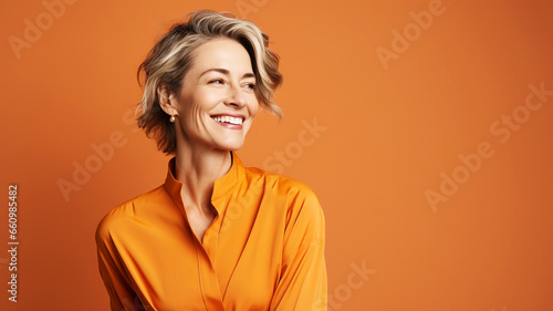 Happy mature businesswoman on an orange solid background
