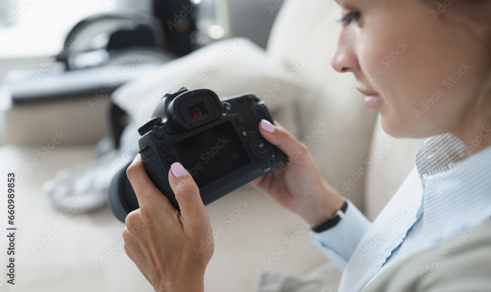 Woman holds black professional camera in her hands. How to become professional photographer yourself from scratch concept - obrazy, fototapety, plakaty 