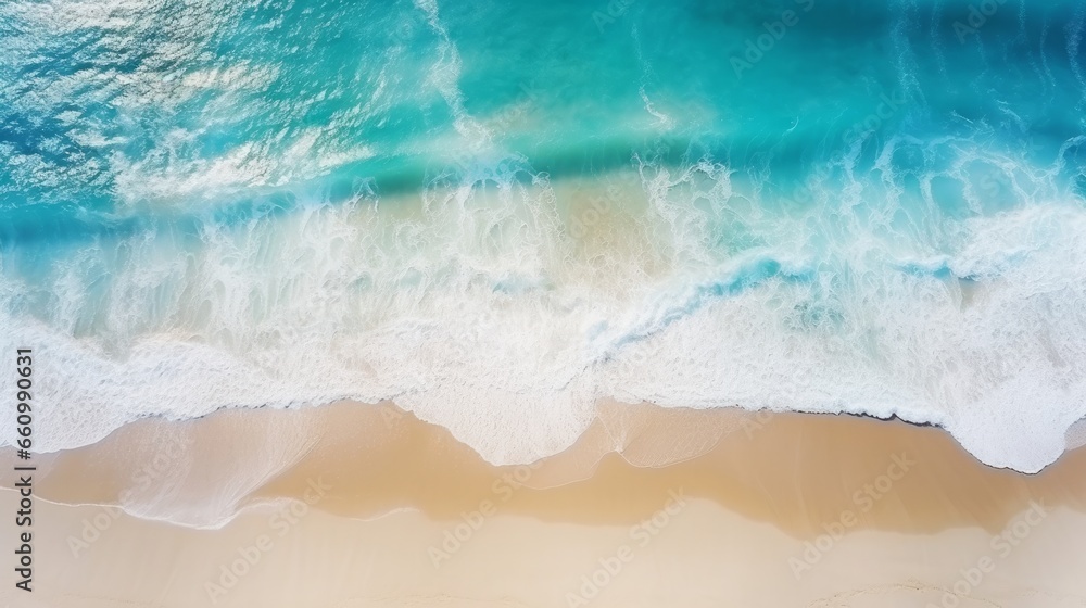 A bird's-eye view of the beach and rolling waves, presenting a captivating turquoise water backdrop. This aerial perspective offers a summer seascape, taken from a drone.